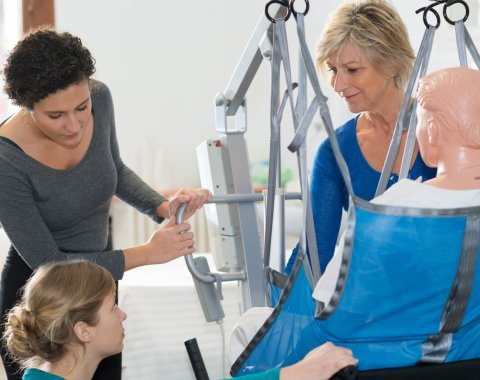 carers moving a dummy in a hoist